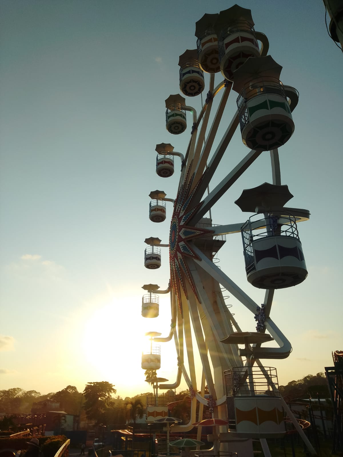 Colorful ferris wheel silhouetted against a Salvadoran sunset