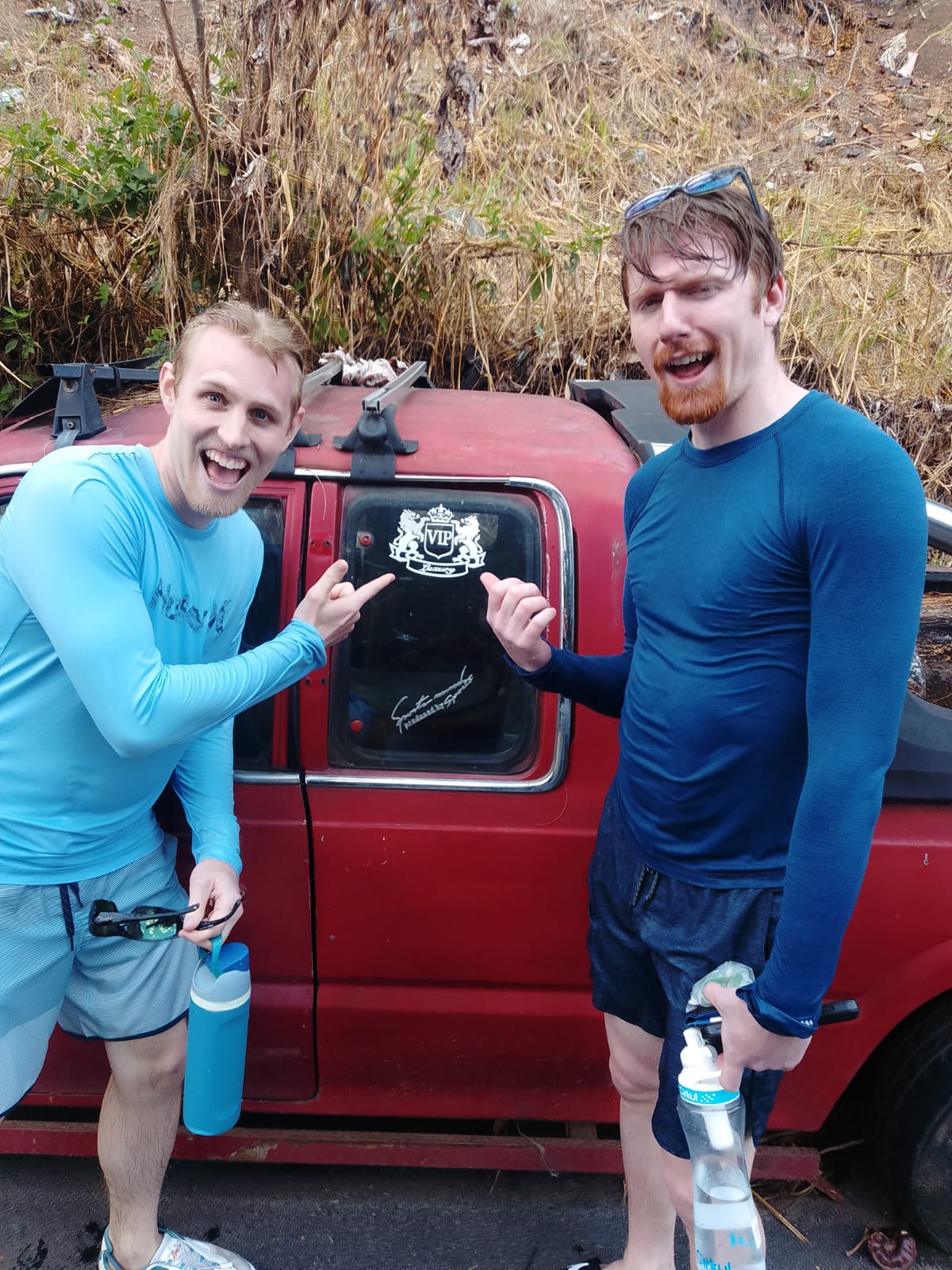 Two guests standing in front of the VIP Tours El Salvador vehicle, pointing at the logo