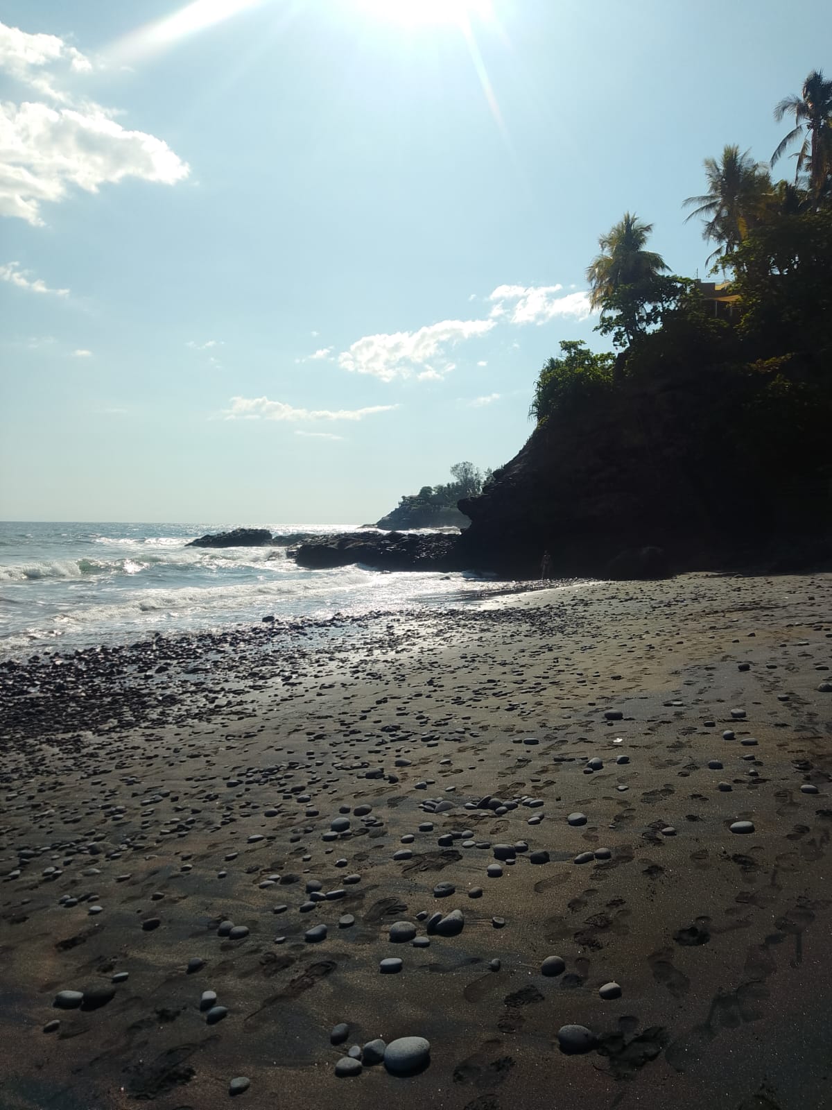 Secluded black-sand cove with volcanic pebbles on the Pacific